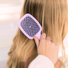 Model brushing hair with the UNbrush Pastel Detangling Hair Brush in Lilac Purple
