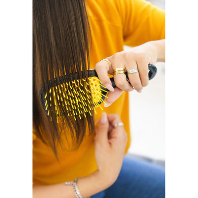 Model brushing hair with the UNbrush Detangling Hair Brush in Sun Ceremony Yellow